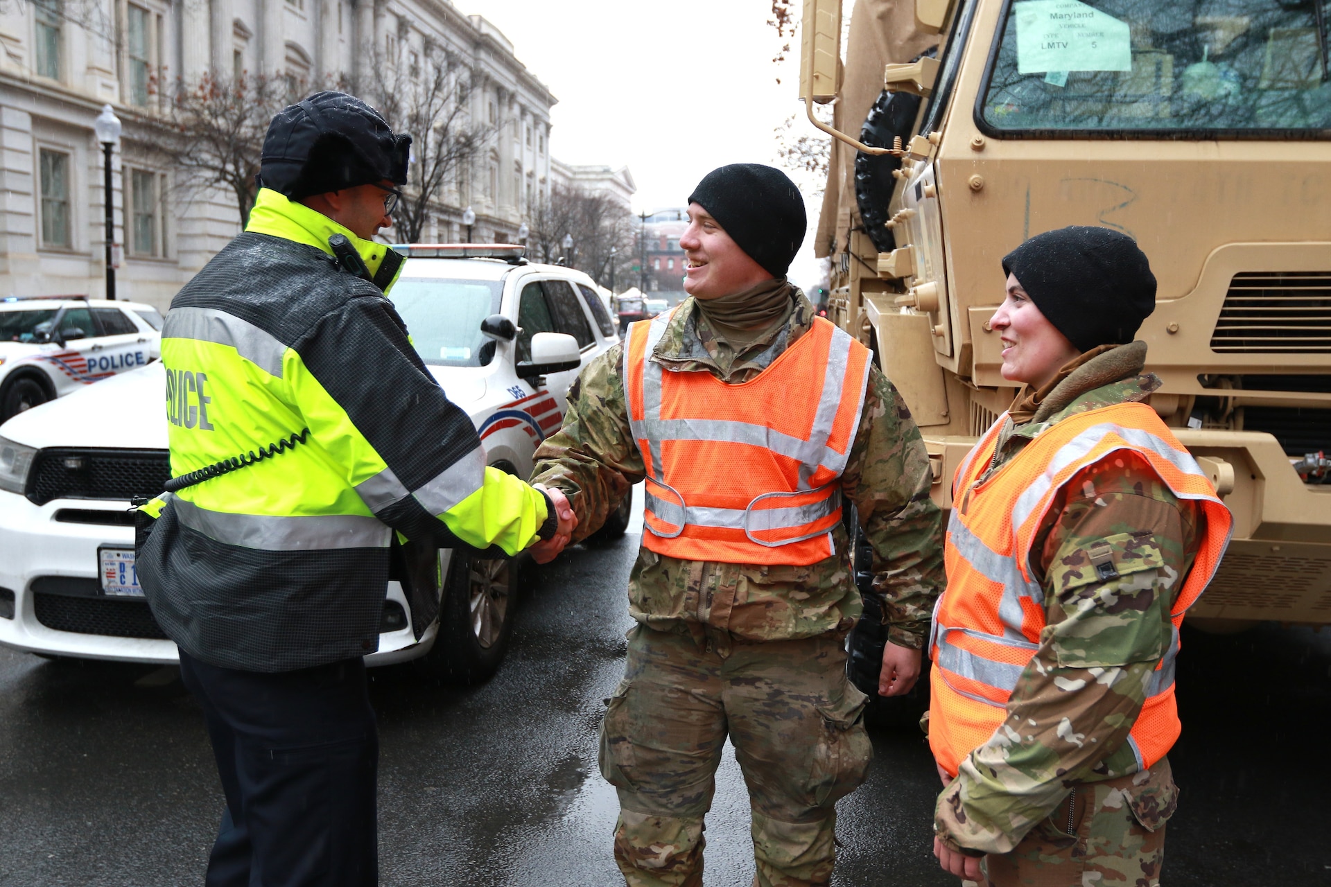 U.S. Army Spc. Kane Lesoine, a motor transport operator assigned to the 121st Transportation Company, 213th Regional Support Group, Pennsylvania Army National Guard, shakes hands with a D.C. Metropolitan Police Department official while providing traffic control in Washington, D.C. as part of Joint Task Force-District of Columbia in support of the 60th Presidential Inauguration, Jan. 19, 2025. Approximately 8,000 National Guard service members from approximately 40 states and territories comprise JTF-DC to support the 60th Presidential Inauguration, continuing a legacy that began in 1789 when their predecessors escorted George Washington to the first inauguration. At the request of civil authorities, these National Guard service members provide critical support such as crowd management, traffic control points, CBRN response, civil disturbance response and sustainment operations. Their expertise and seamless collaboration with interagency partners help ensure a safe and peaceful transition of power during this historic event. (U.S. Army National Guard photo by Sgt. 1st Class Shane Smith)