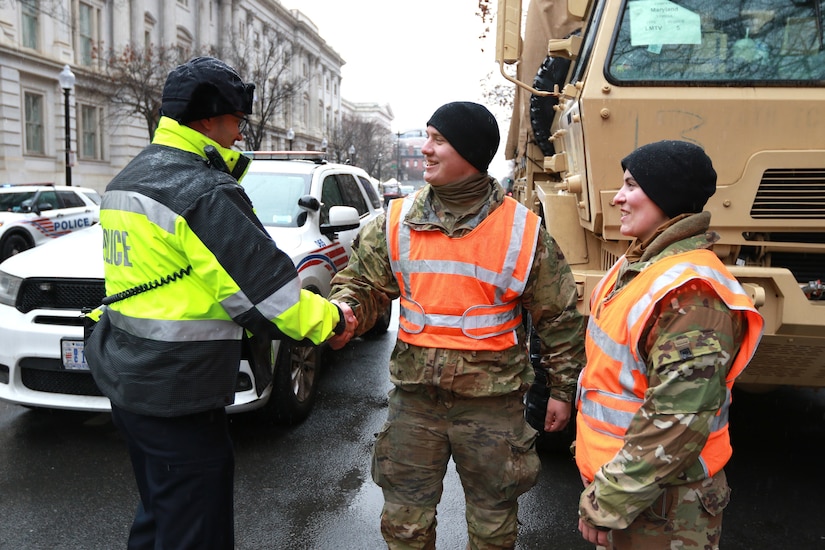 U.S. Army Spc. Kane Lesoine, a motor transport operator assigned to the 121st Transportation Company, 213th Regional Support Group, Pennsylvania Army National Guard, shakes hands with a D.C. Metropolitan Police Department official while providing traffic control in Washington, D.C. as part of Joint Task Force-District of Columbia in support of the 60th Presidential Inauguration, Jan. 19, 2025. Approximately 8,000 National Guard service members from approximately 40 states and territories comprise JTF-DC to support the 60th Presidential Inauguration, continuing a legacy that began in 1789 when their predecessors escorted George Washington to the first inauguration. At the request of civil authorities, these National Guard service members provide critical support such as crowd management, traffic control points, CBRN response, civil disturbance response and sustainment operations. Their expertise and seamless collaboration with interagency partners help ensure a safe and peaceful transition of power during this historic event. (U.S. Army National Guard photo by Sgt. 1st Class Shane Smith)