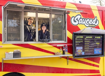 Cook and driver Brando Jativa and server Elizabeth Ritalo await their next customer inside the "Sauced" food truck Nov. 13, 2024, at Naval Base Kitsap-Bangor, Silverdale, Washington. The food truck specializes in Filipino, Hawaiian and Mexican cuisine. (U.S. Navy photo by Wendy Hallmark)