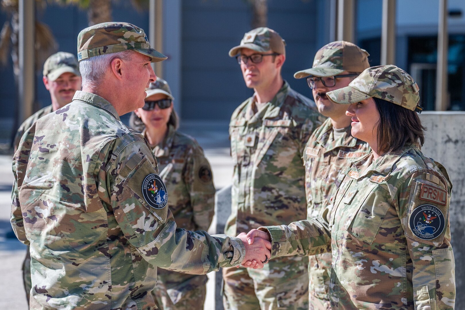 A military leader presents a coin into the hand of a military member for recognition.