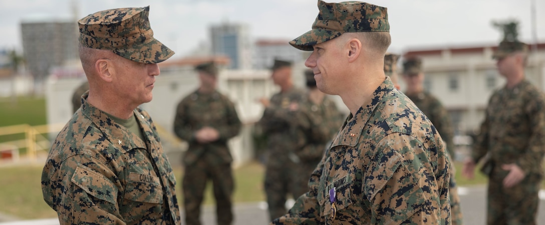 U.S. Marine Corps Brig. Gen. Kevin G. Collins, left, the commanding general of 3rd Marine Logistics Group (3rd MLG), expresses his appreciation to Chief Warrant Officer 2 William Faffler, right, a visual information officer with 3rd MLG, during a Purple Heart ceremony on Camp Kinser, Okinawa, Japan, Jan. 6, 2025. Faffler received two Purple Hearts, both for wounds sustained during combat operations in support of Operation Enduring Freedom in Helmand Province, Afghanistan, May and October of 2010. (U.S. Marine Corps photo by Lance Cpl. Weston Brown)