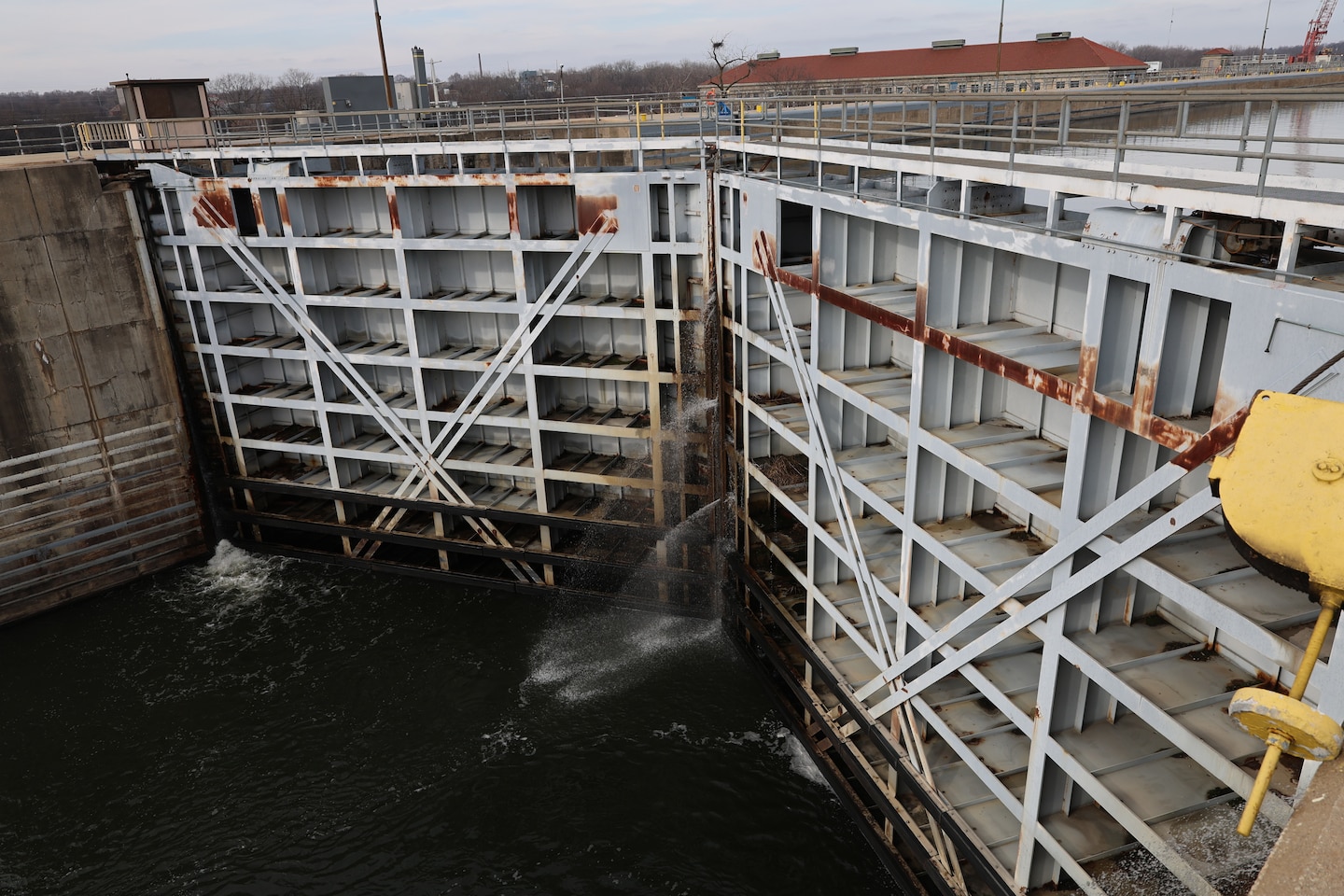 Large white gate holds back river water.