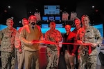 Vice Adm. Fred Kacher, center, commander of U.S. 7th Fleet, opens the new Navigation, Seamanship, and Shiphandling Trainer (NSST) facility during a ribbon-cutting ceremony at Commander, Fleet Activities Yokosuka (CFAY), Jan. 16, 2025. With Kacher are Rear Adm. Greg Newkirk, left, commander of Task Force 70, Capt. Dave Huljack, deputy commodore of Destroyer Squadron (DESRON) 15, Capt. Shockey Snyder, back, commander of Naval Surface Group Western Pacific, and NSST team members. The new facility assists the Yokosuka waterfront with seamanship and navigation training for surface forces and offers a full bridge simulator. (U.S. Navy photo by Mass Communication Specialist 1st Class Caroline H. Lui)