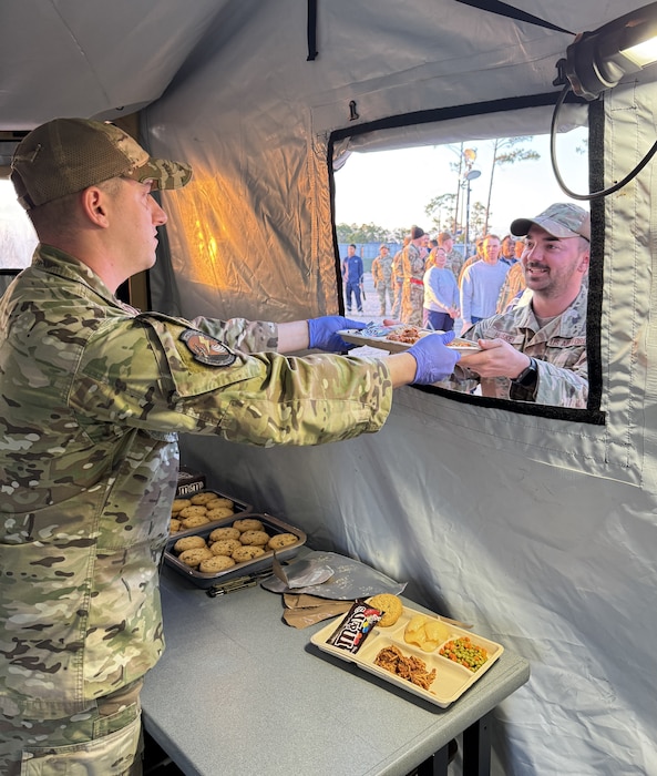 An Airmen passes a meal through a window in a field tent.