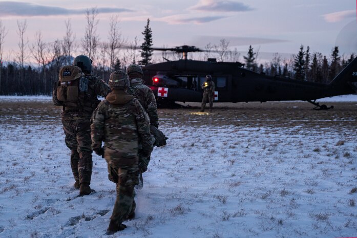 oldiers assigned to Charlie Company, 25th Brigade Support Battalion, 1st Infantry Brigade Combat Team, 11th Airborne Division, move a simulated casualty to a UH-60 Blackhawk assigned to 1-52D General Support Aviation Battalion, Arctic Aviation Command, 11th Airborne Division, during a medical evacuation rehearsal ahead of Joint Pacific Multinational Readiness Center 25-02, at the Donnelly Training Area near Fort Greely, Alaska, Jan. 18, 2025.