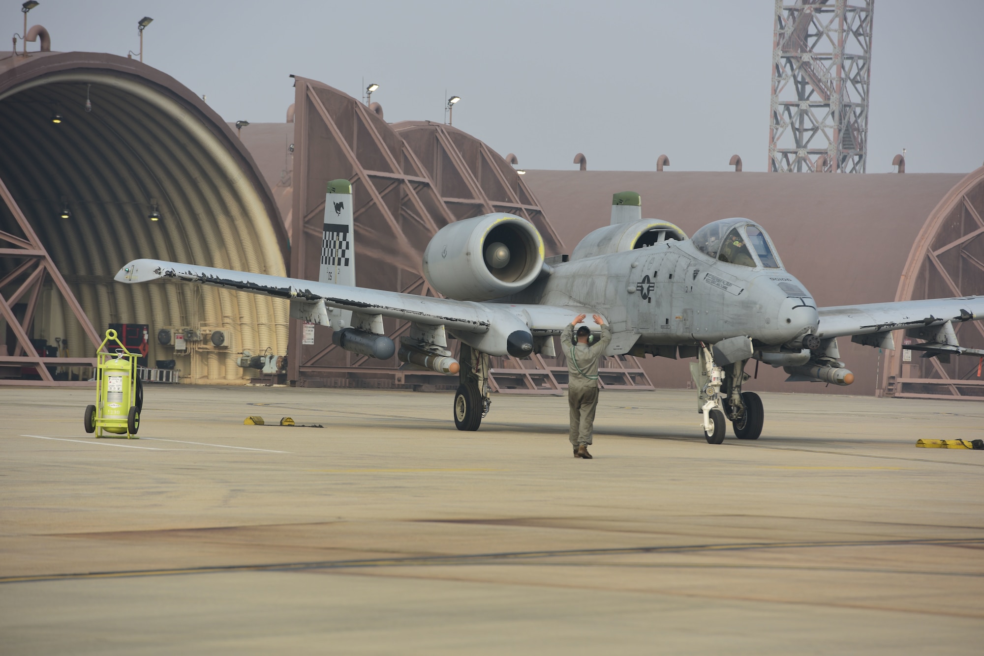A U.S. Air Force crew chief guides an A-10 Thunderbolt II pilot assigned to the 25th Fighter Squadron away from a hangar, at Osan Air Base