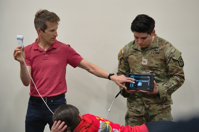 Dr. Dan Cushman (University of Utah) and Sgt. Lopez (WRAIR-West) demonstrate how to use an ultrasound in an ultrasound training session hosted by WRAIR-West for Holistic Health and Fitness. (Photo Credit: Sean Hall)