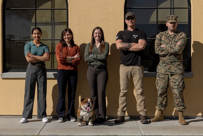 U.S. Marine Corps Lance Cpl. Bruno, the Marine Corps Recruit Depot San Diego and Western Recruiting Region mascot, poses for a photo with members of the Criminal Investigation Division, Headquarters and Service Battalion, at Marine Corps Recruit Depot San Diego, California, Dec. 10, 2024. The mascot’s job is to boost morale, participate in outreach work, and attend events and ceremonies. (U.S. Marine Corps photo by Lance Cpl. Jacob B. Hutchinson)