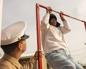 A Stony Point High School student performs pull-ups in front of a U.S. Marine with Recruiting Sub-Station Round Rock, Recruiting Station Austin during a school visit at Stony Point High School in Round Rock, Texas, Jan. 14, 2025. During this visit, the Marines shared information about the Marine Corps and conducted a uniform inspection for Stony Point High School Naval Junior Reserve Officer Training Corps cadets. (U.S. Marine Corps photo by Cpl. Jose D. Cruz)