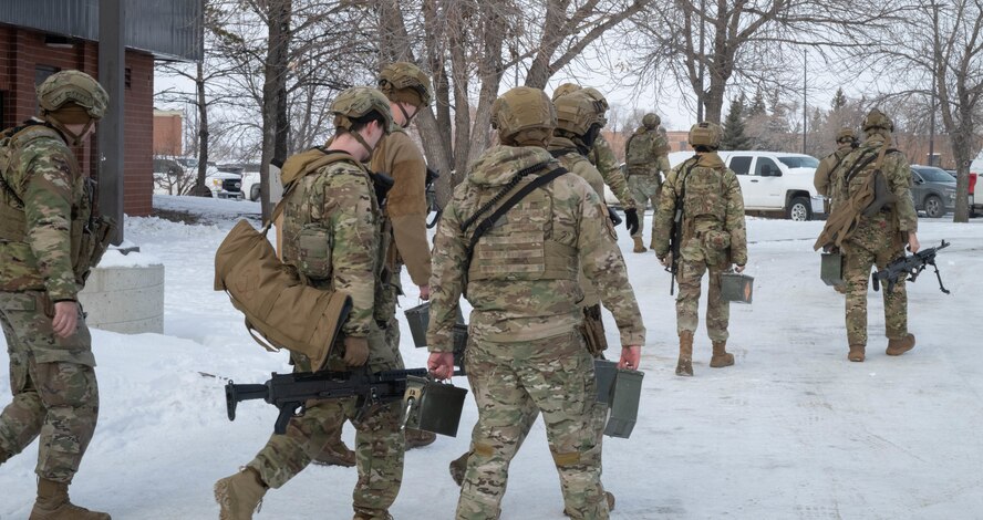 Airmen assigned to the 91st Missile Security Forces Squadron carry their gear to trucks en route to a Missile Alert Facility (MAF) during an exercise at Minot Air Force Base, North Dakota, Jan. 14, 2025. The Airmen that are a part of the exercise must be fully ready to help resolve the simulated assault on the MAF effectively. (U.S. Air Force photo by Airman 1st Class Wesley Davies)