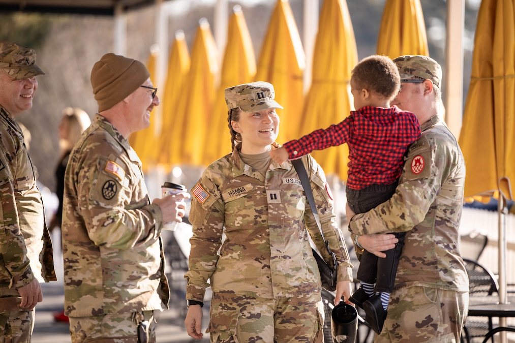 Several guardsmen interact with a child, while one guardsman holds the child aloft.