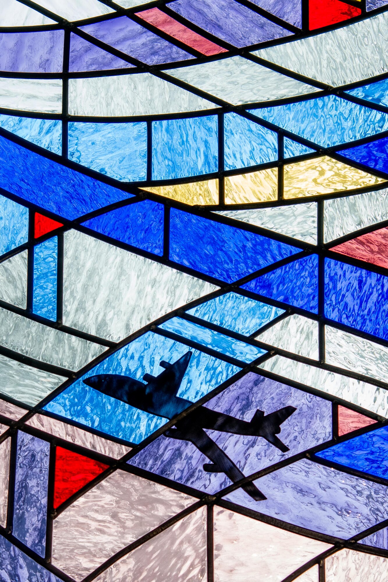 A plane flies across a sky of stained glass in a Chapel window