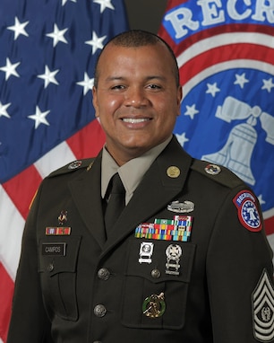 Photo of Command Sgt. Maj. U.S. Army Soldier posing for command photo in front of U.S. flag and United States Recruiting Command (USAREC) flag.