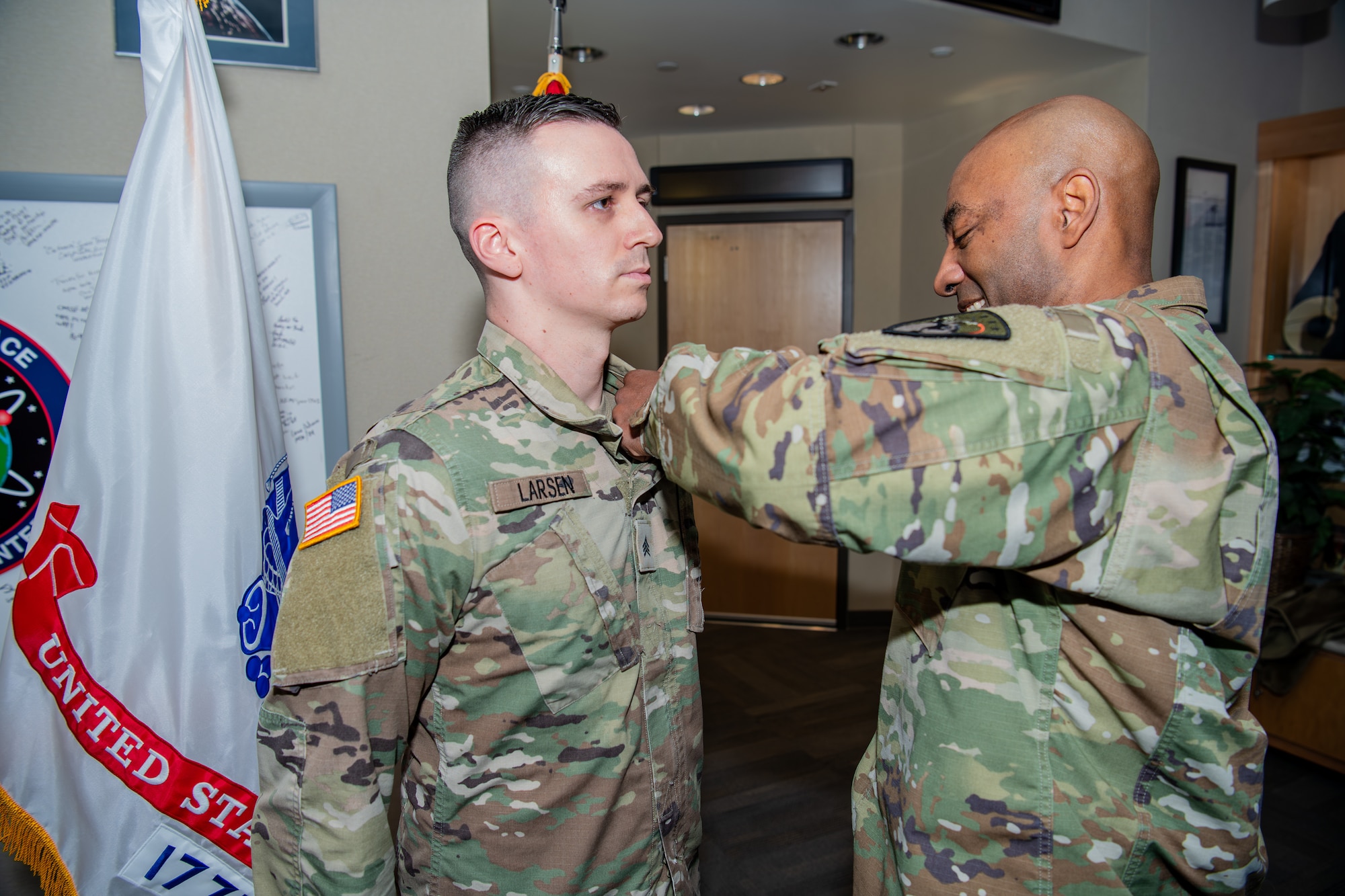 Man in military uniform pins another man in military uniform