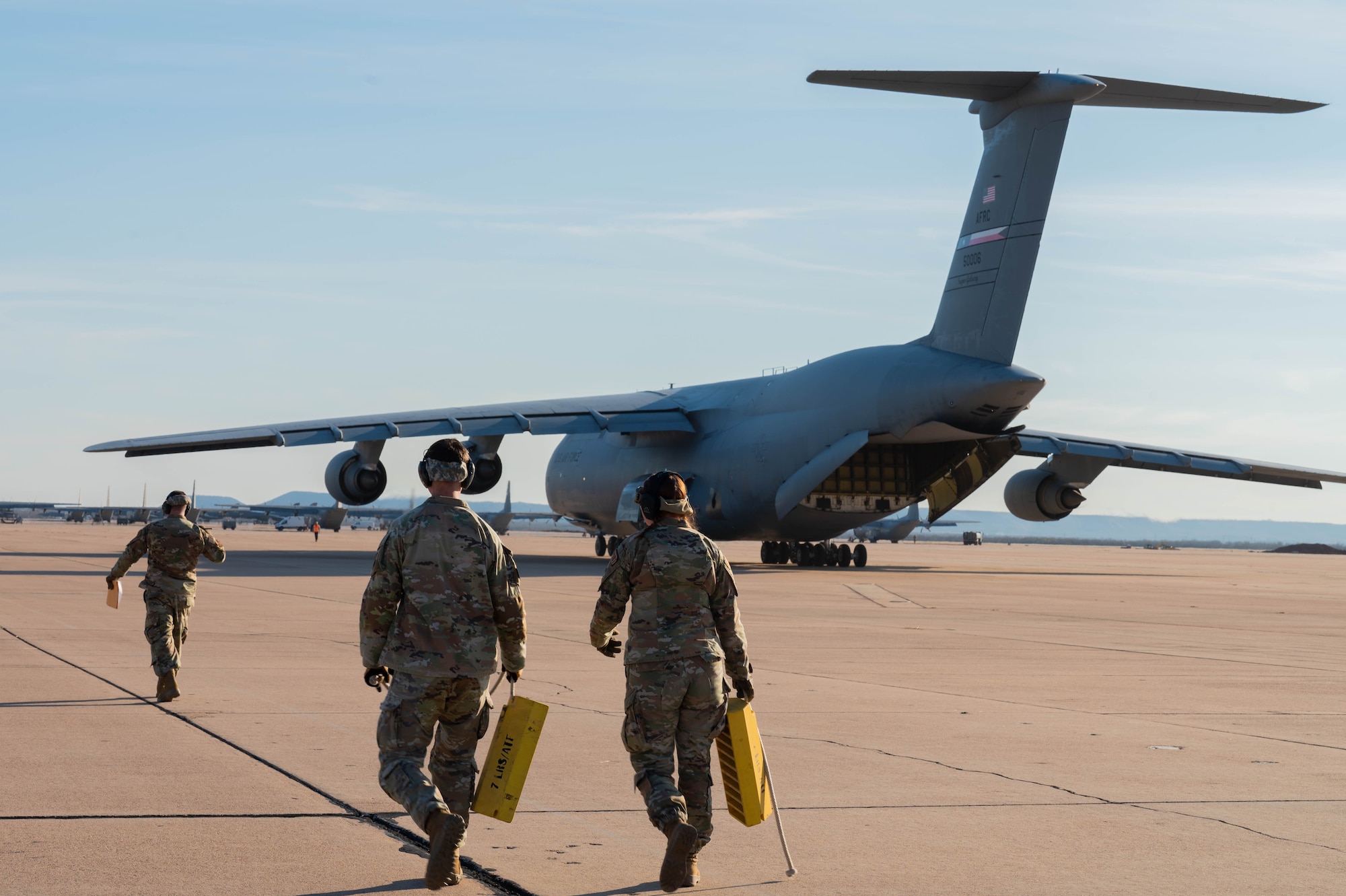 Airmen from the 7th Logistics Readiness Squadron air transportation function walk toward a C-5M Super Galaxy from the 68th Airlift Squadron, Joint-Base San Antonio-Lackland, Texas, at Dyess Air Force Base, Texas, Jan. 16, 2025. The 7th LRS staged 35,730 pounds of rice to transport to Honduras and El Salvador for humanitarian aid. (U.S. Air Force photo by Senior Airman Alondra Cristobal Hernandez)
