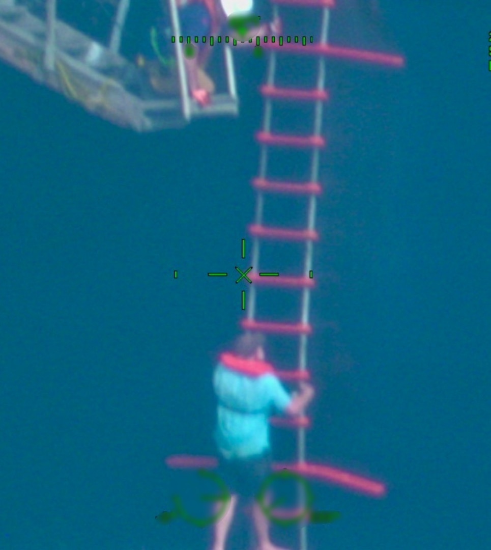 A Coast Guard aircrew maintains air coverage of a survivor climbing a ladder to go onboard the container ship Coqui, Jan. 21, 2025.  The man is one of four survivors who moments earlier were forced to abandon the sailing vessel Mariposa after it sank in Atlantic Ocean waters north of Dominican Republic.  The four U.S. boaters were rescued by fishermen from the fishing vessel Bonanza who transferred the survivors to the U.S. flagged container ship, Coqui, for their transport to Jacksonville, Fla. (U.S. Coast Guard photo)