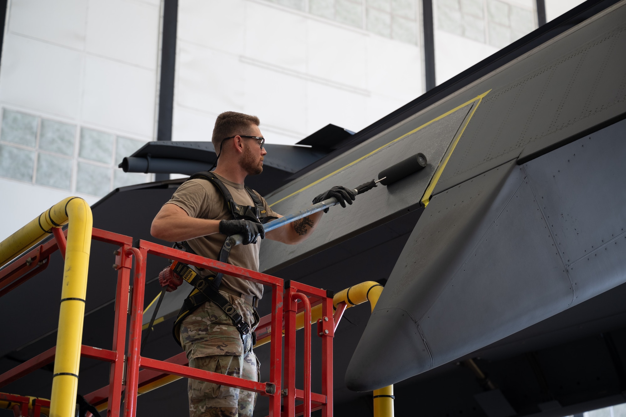 Airman uses paint roller on a C-17 Globemaster III wing.
