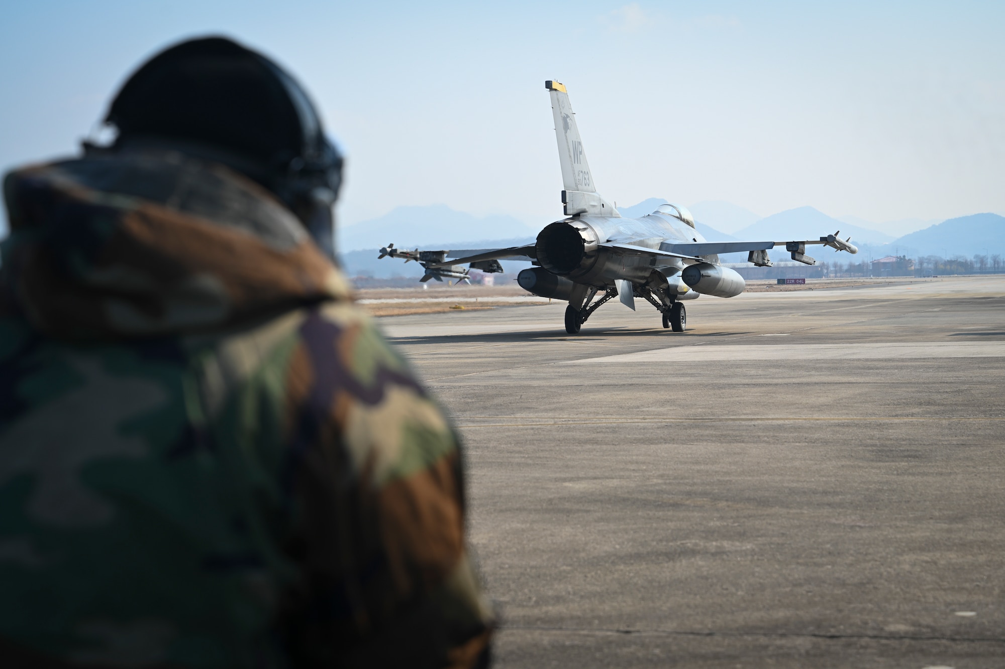 Senior Airman Xavier Cubas, 35th Fighter Generation Squadron dedicated crew chief, stands watch as an F-16 Fighting Falcon from the 80th Fighter Squadron taxis to the runway after servicing at Gwangju Air Base, Republic of Korea, Jan. 13, 2025.
