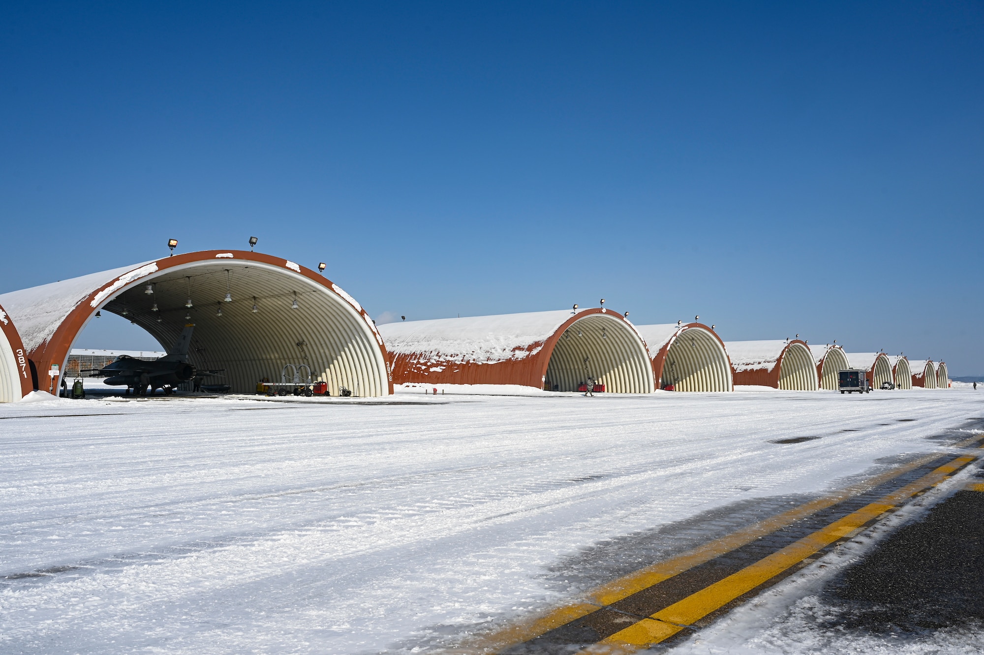 A row of hangars is lined up on the flight line.