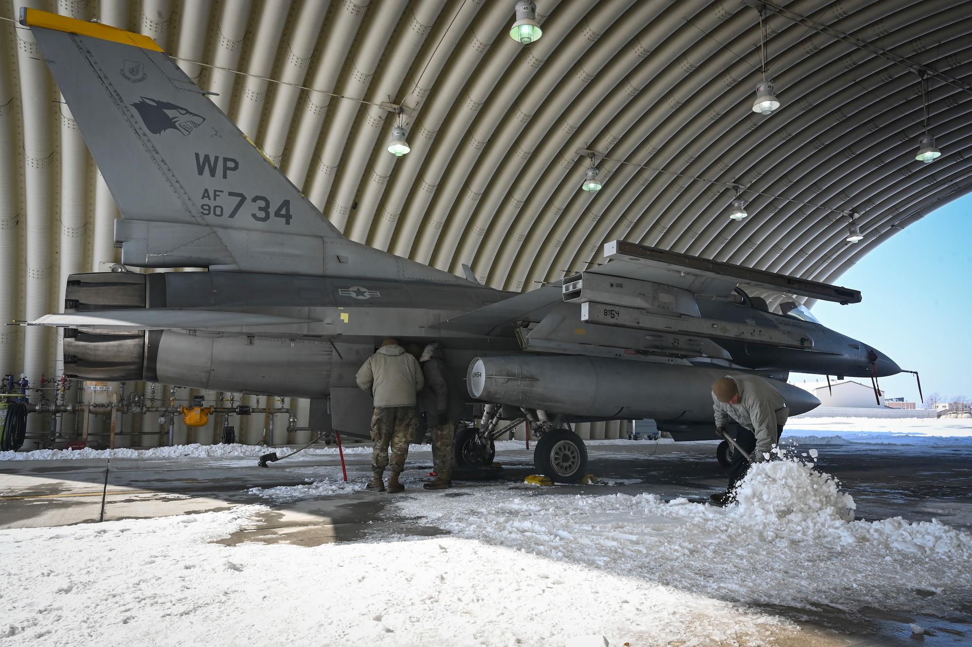 Airmen assigned to the 35th Fighter Generation Squadron conduct maintenance on an F-16 Fighting Falcon aircraft and remove snow from the area before Beverly Pack 25-1.