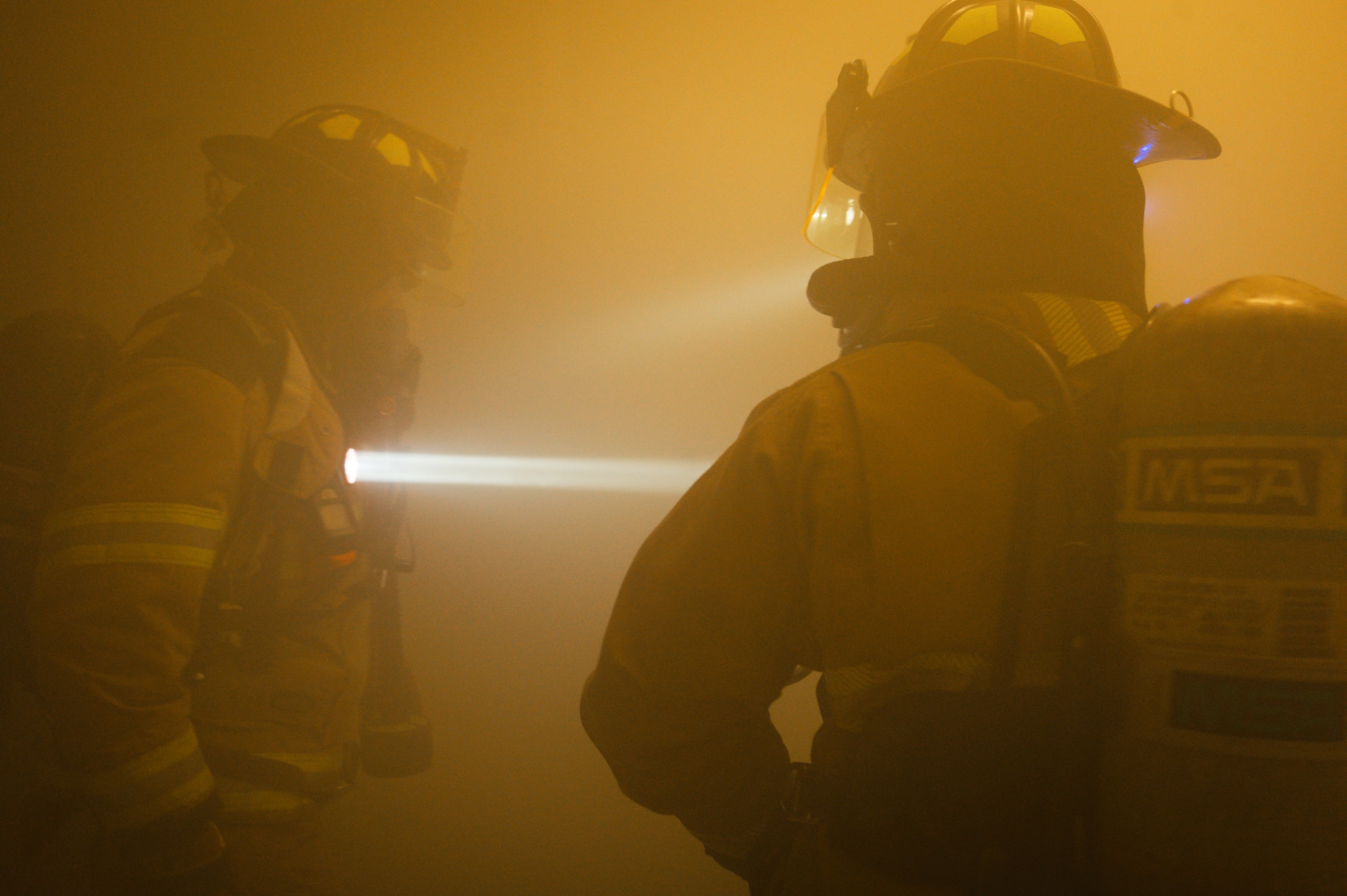 U.S. Air Force Staff Sgt. Jahryd Hopkins, 8th Civil Engineering Squadron lead firefighter, left, and Airman 1st Class Scott Gales, 8th CES firefighter, right, search for the source of a simulated fire.