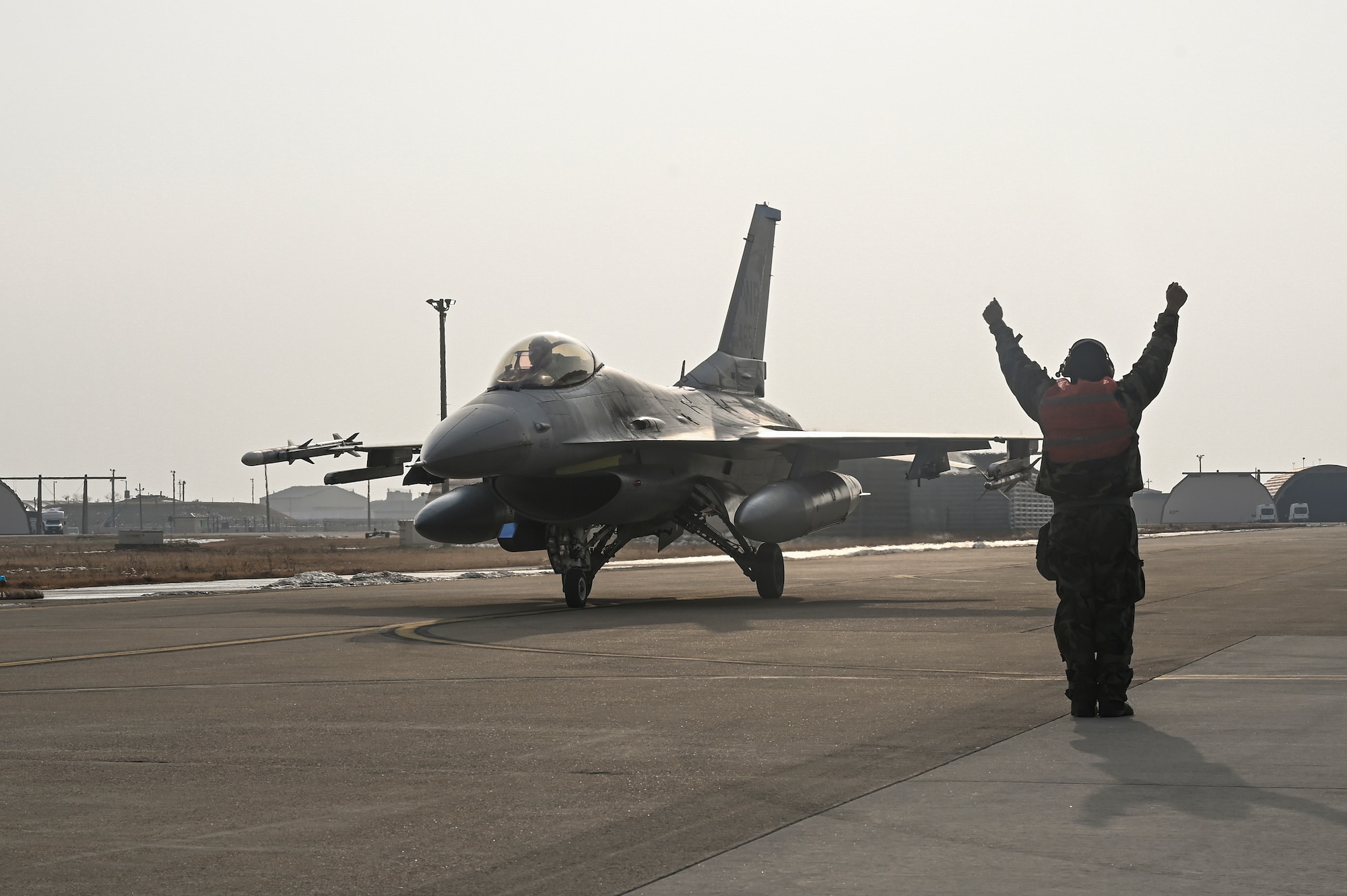 U.S. Air Force Staff Sgt. Nelson Lumibao, 35th Fighter Generation Squadron F-16 Fighting Falcon dedicated crew chief, marshals an F-16 Fighting Falcon aircraft during Beverly Pack 25-1.