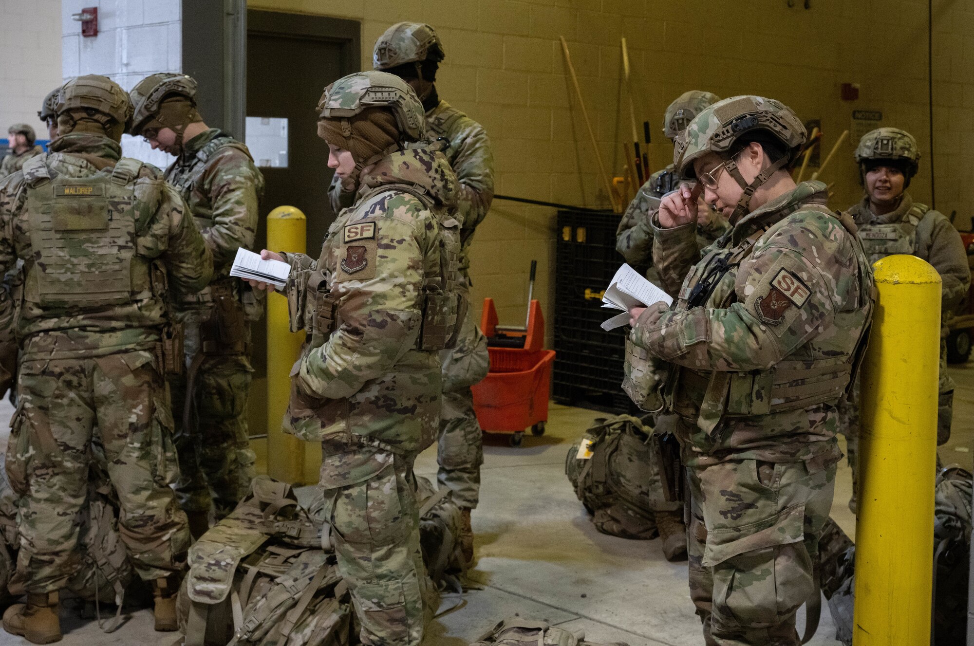 Airmen assigned to the 91st Missile Security Forces Squadron study procedures during an exercise in order to remain ready before departing for a Missile Alert Facility during an exercise at Minot Air Force Base, North Dakota, Jan. 14, 2025. The booklets are filled with procedures and rules that the airmen must follow during the exercise. (U.S. Air Force photo by Airman 1st Class Wesley Davies)