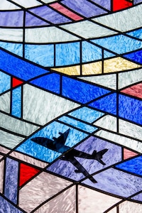A plane flies across a sky of stained glass in a Chapel window