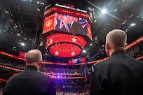 Shot behind two service members looking at Jumbotron in the background