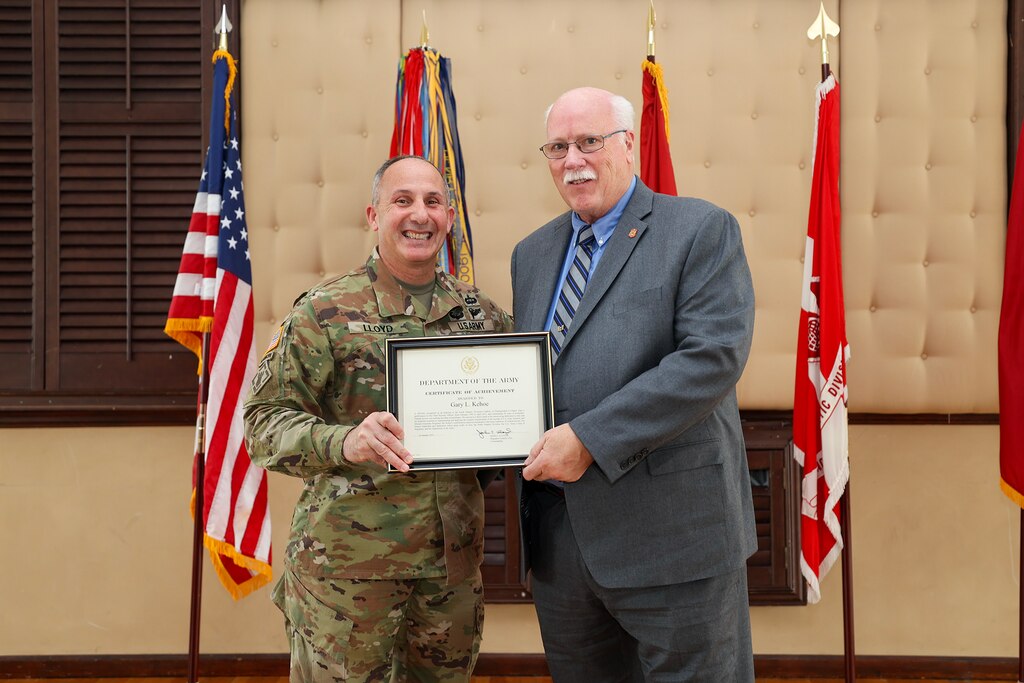 Brig. Gen. John P. Lloyd, U.S. Army Corps of Engineers, North Atlantic Division commander and division engineer, presents Gary L. Kehoe, a retired NAD chief security officer, with a Certificate of Achievement during an all-hands ceremony at the Fort Hamilton Community Club in Brooklyn, New York. During the event, Kehoe was inducted into the NAD Gallery of Distinguished Civilians after a 26-year federal career, becoming the 26th inductee selected for the honor since the gallery’s inception in the mid-1900s.