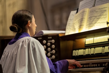 An organist plays their instrument while reading a music sheet
