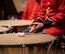 A band member waits with hands together on lap with their drum next to them