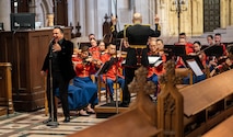 A band plays their instruments while opera singer is singing