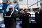 Sailors salute the ensign during a retirement ceremony in  Pensacola, Fla.