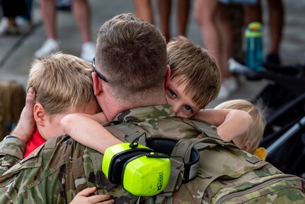 man hugs children