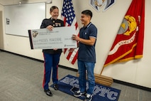U.S. Marine Corps Capt. Brianna K. LeCompte, the executive officer of Recruiting Station Austin, presents the Naval Reserve Officer Training Corps scholarship to Moises Aguirre during the presentation of the NROTC scholarship at Hendrickson High School in Pflugerville, Texas, Jan. 15, 2025. Students selected for this prestigious scholarship program must uphold strict physical standards and successfully complete additional military courses while maintaining normal college coursework responsibilities. (U.S. Marine Corps photo by Cpl. Jose D. Cruz)
