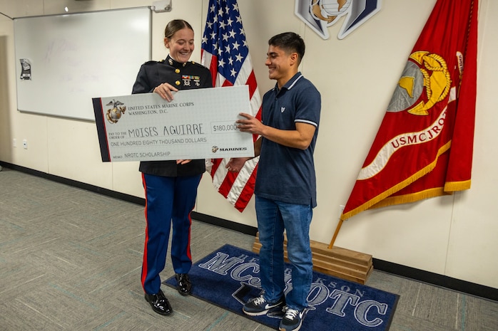 U.S. Marine Corps Capt. Brianna K. LeCompte, the executive officer of Recruiting Station Austin, presents the Naval Reserve Officer Training Corps scholarship to Moises Aguirre during the presentation of the NROTC scholarship at Hendrickson High School in Pflugerville, Texas, Jan. 15, 2025. Students selected for this prestigious scholarship program must uphold strict physical standards and successfully complete additional military courses while maintaining normal college coursework responsibilities. (U.S. Marine Corps photo by Cpl. Jose D. Cruz)