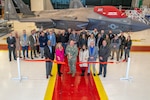 Capt. Randy Berti, center, cuts the ribbon during a ribbon cutting ceremony to celebrate the completion of its F-35 Lightning II expansion project.