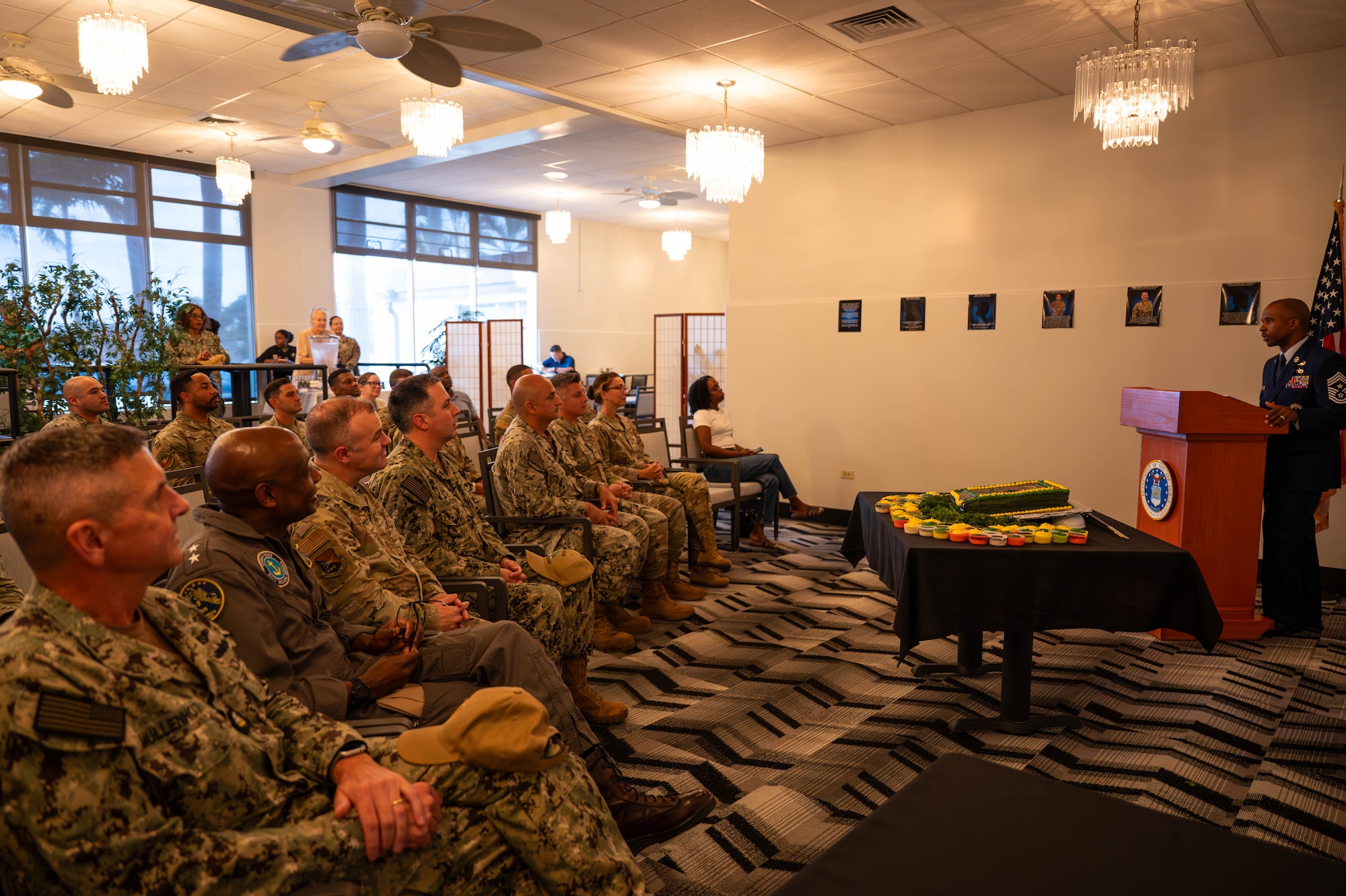 Airman at podium speaking to a group of serves members