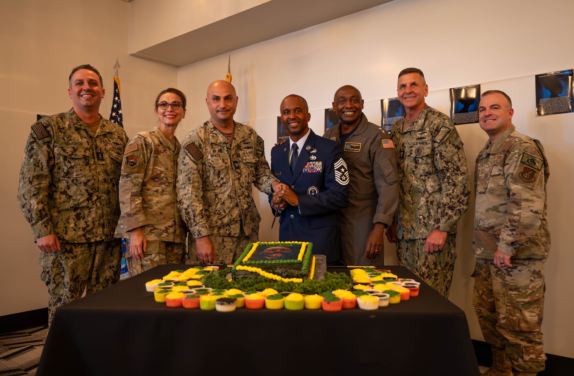 Group of service members posing for picture about to cut cake with a sward