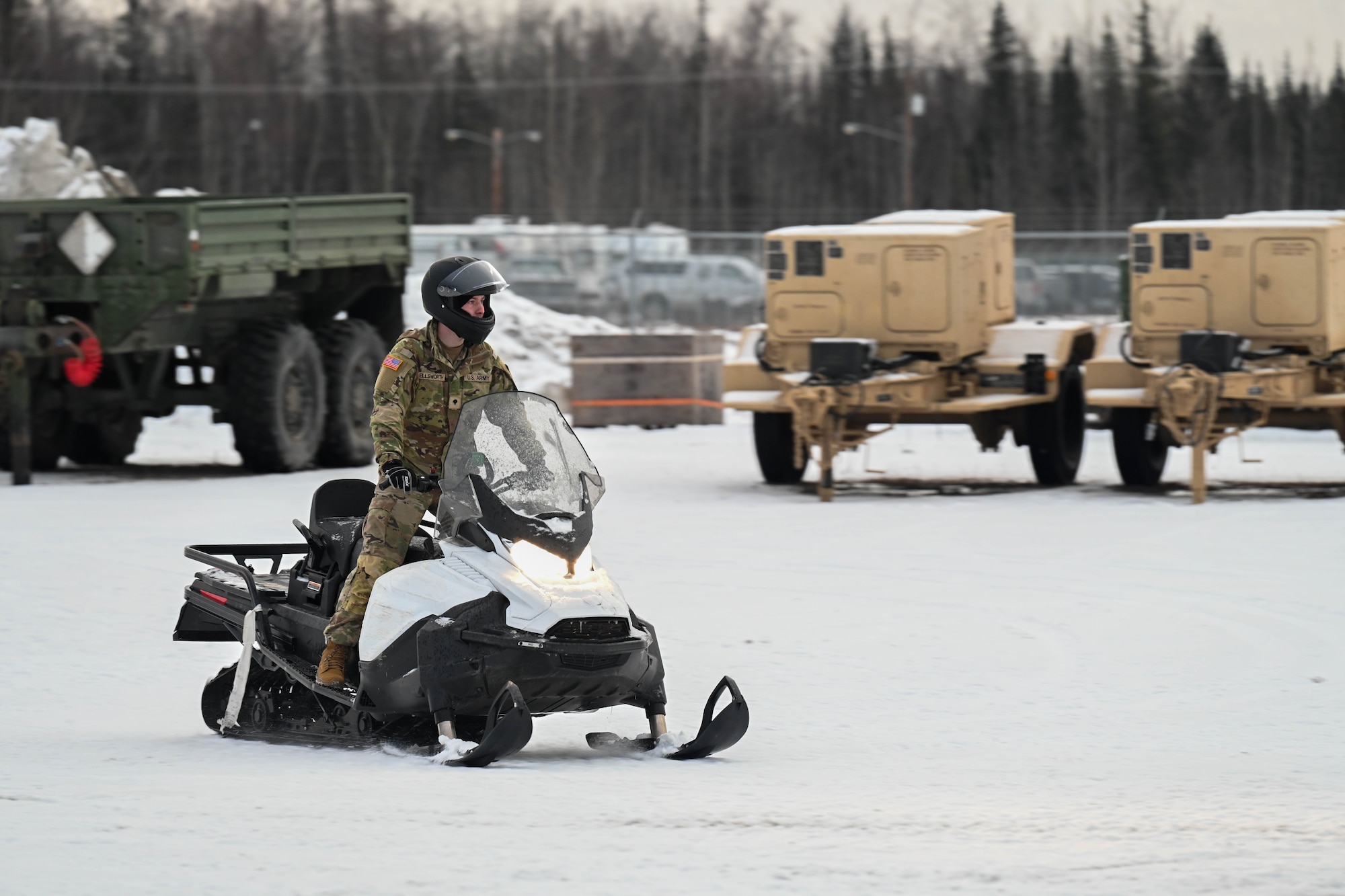 U.S. Army Spc. Brady Ellsworth, 2nd Brigade Infantry Combat Team, 11th Airborne Division, drives a snowmachine on Joint Base Elmendorf-Richardson, Alaska, to be loaded onto a transport vehicle Jan. 6, 2025 to prepare for the Joint Pacific Multinational Readiness Center exercise at Fort Wainwright.