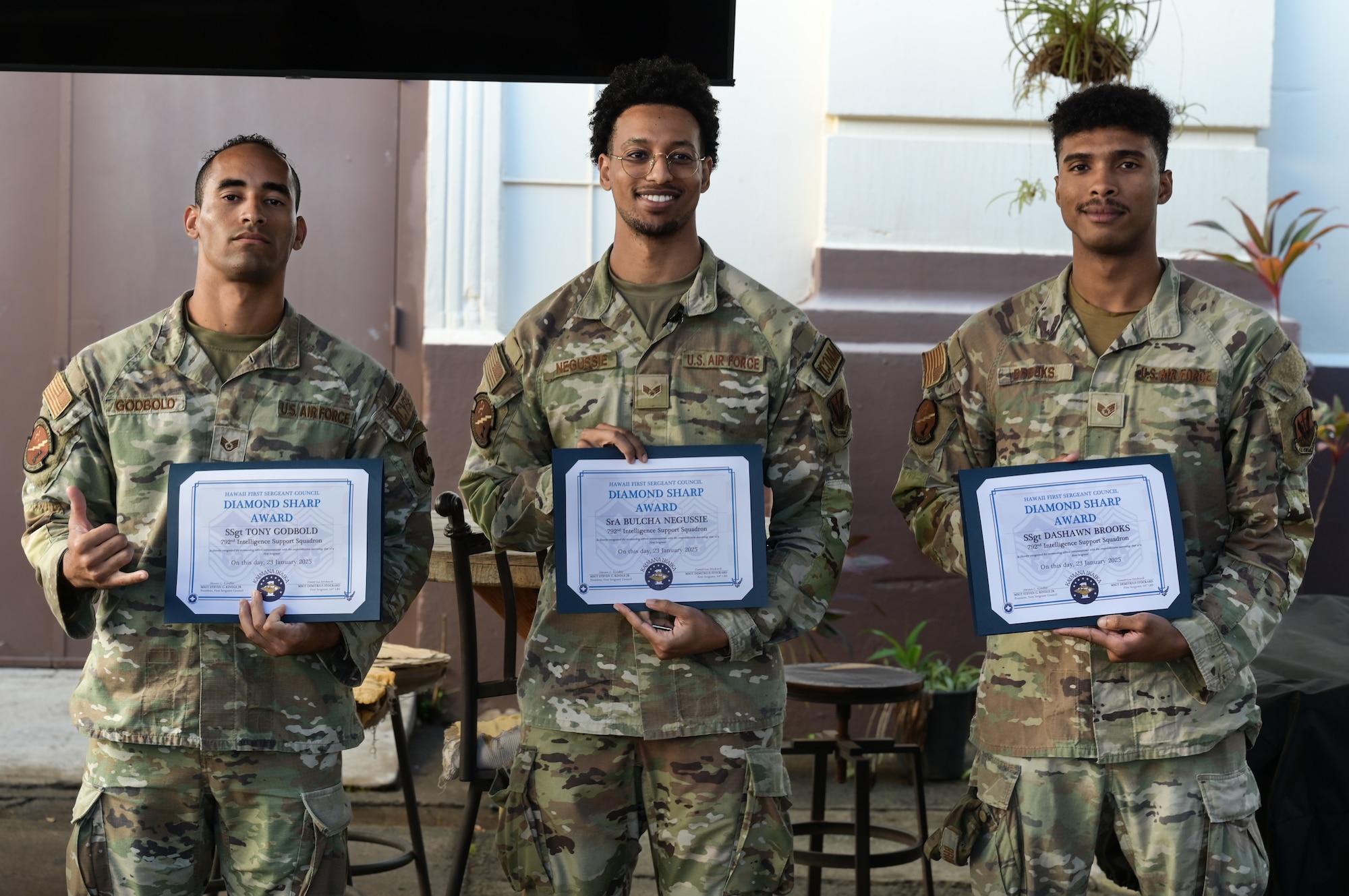 Three Airmen stand with documents in hand.