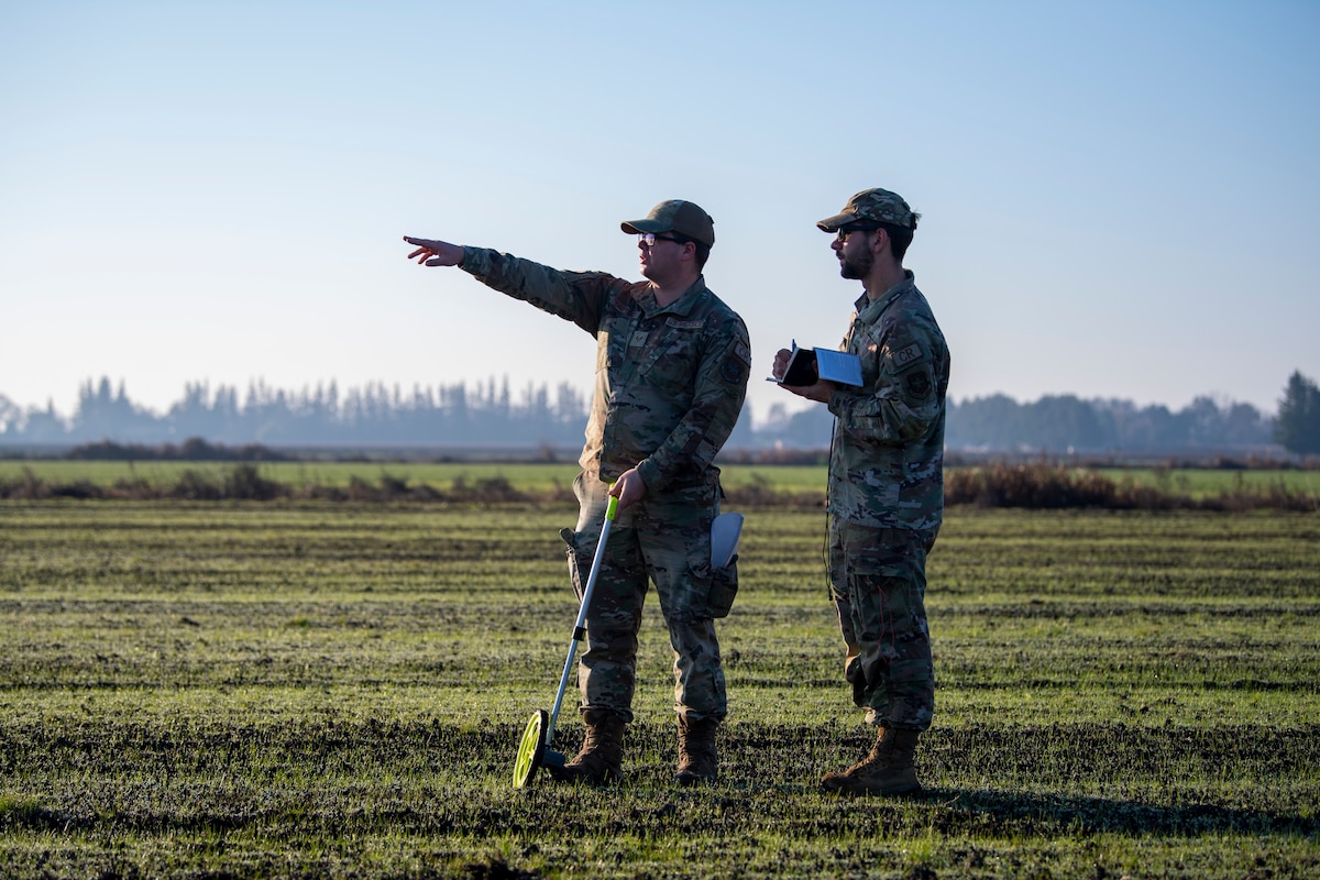 U.S. Air Force Staff Sgt. Wesley Shepherd, left, 821st Contingency Response Squadron landing zone safety officer, points to end of a flight line with U.S. Air Force Staff Sgt. Samson Rice, right, 921st CRS LZSO, in Rio Vista, California, Jan. 10, 2025.