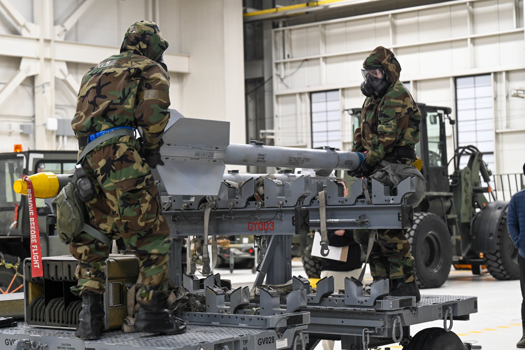 U.S. Air Force Airman 1st Class Aryan Guerrero, 3rd Munitions Squadron, and Airman 1st Class Breeann Hamilton, 3rd Munitions Squadron, competing for the 525 Fighter Generation Squadron lifting an inert AIM-9M Sidewinder to be loaded into the side internal weapons bay of an F-22 Raptor during the bomb portion of a load competition on Joint Base Elmendorf-Richardson, Alaska, Jan. 10, 2025.