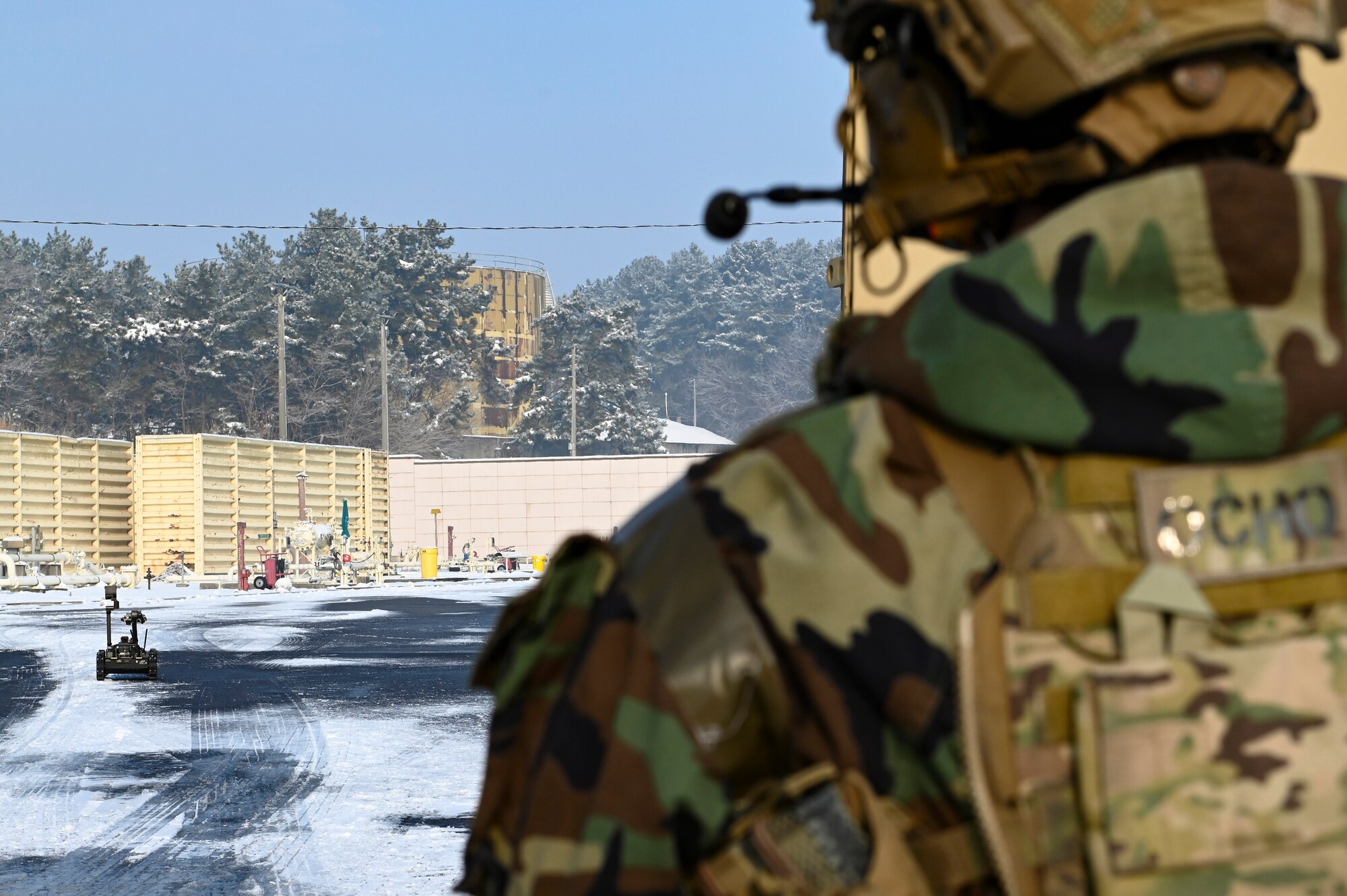 U.S. Air Force Staff Sgt. Brian Price, 8th Civil Engineer Squadron explosive ordnance disposal team leader, watches as the man transportable robotic system is driven toward a simulated downed drone and ordnance during Beverly Pack 25-1.