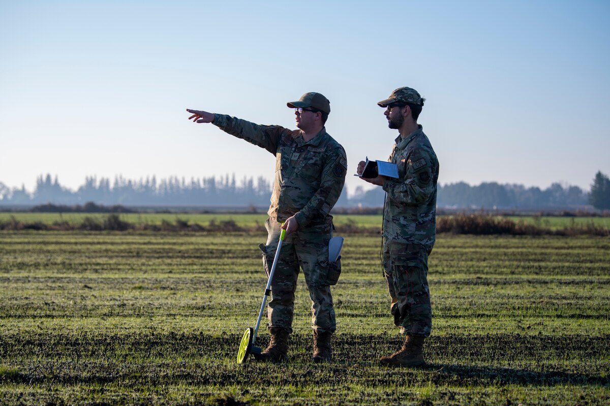 U.S. Air Force Staff Sgt. Wesley Shepherd, left, 821st Contingency Response Squadron landing zone safety officer, points to end of a flight line with U.S. Air Force Staff Sgt. Samson Rice, right, 921st CRS LZSO, in Rio Vista, California, Jan. 10, 2025.
