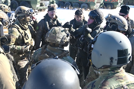 A Marine CH-53 Super Stallion helicopter pilot from Marine Heavy Helicopter Squadron 772 out of Joint Base Maguire-Dix-Lakehurst, New Jersey, gives instructions to Air Force sling-load specialists from the 621st Contingency Response Group and Soldiers from the Fort Indiantown Gap Training Center prior to an operation to air-lift eight decommissioned Army Stryker vehicles to Fort Indiantown Gap’s impact area Jan. 22, 2025. (Pennsylvania National Guard photo by Brad Rhen)
