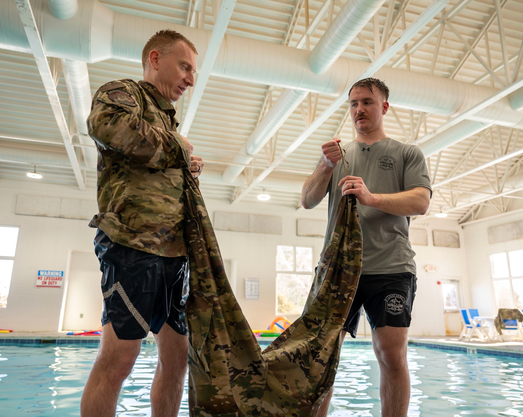 Survival, evasion, resistance, escape specialist Senior Airman Christopher VanHeuvelen demonstrates a drownproofing technique at Scott Air Force Base on Jan. 16, 2025. Drownproofing is a survival technique that involves making a flotation device out of a uniform while treading water. (U.S. Air Force photo by Rachel Sansano)