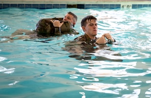 Two Airmen learn drownproofing techniques at Scott Air Force Base on Jan. 16, 2025. Drownproofing is a survival technique that involves making a flotation device out of a uniform while treading water. (U.S. Air Force photo by Rachel Sansano)