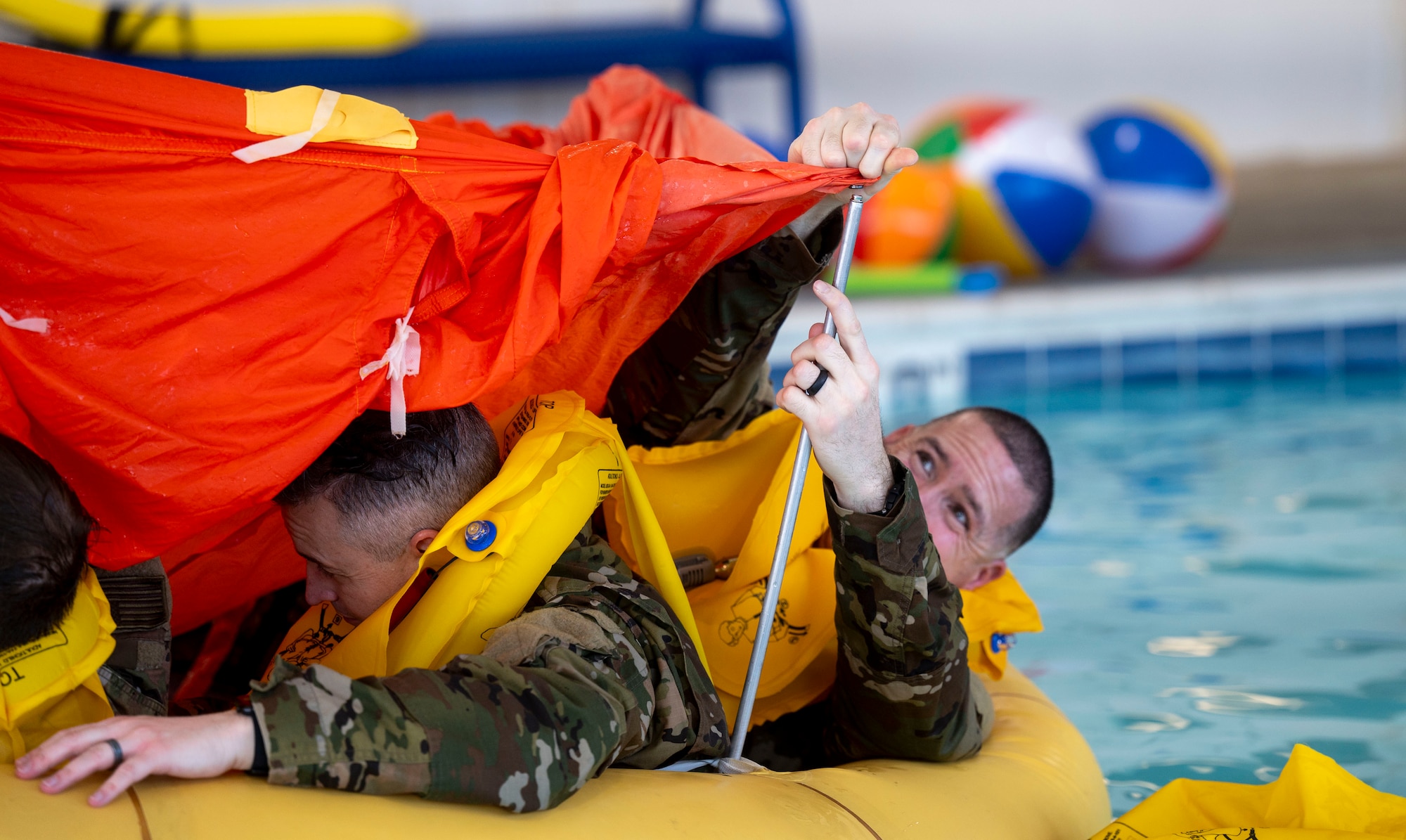 An Airman attaches a cover to his crew’s life raft during water survival training at Scott Air Force Base on Jan. 16, 2025. This training was taught by survival, evasion, resistance, escape specialists, who are extensively trained in personnel recovery operations. (U.S. Air Force photo by Rachel Sansano)